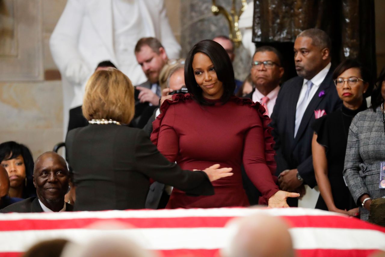 Cummings' wife extends her arms to Pelosi during the memorial service.