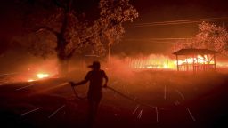 Susi Weaver, the manger for the Hawkeye Ranch in the Mayacamas Mountains above Geyserville, Calif., sprays down the dry brush as the the Kincade fire delivers firebrands across the property, Thursday, Oct. 24, 2019. (Kent Porter/The Press Democrat via AP)