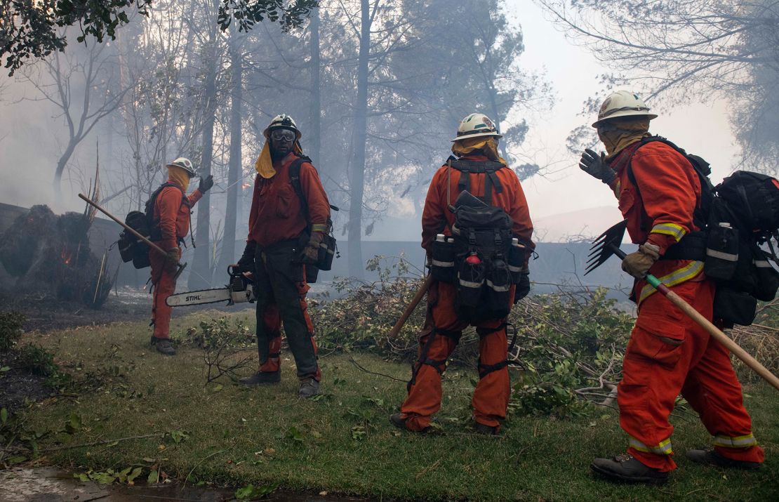 Firefighters from Holton Fire Camp 16 work to contain the Tick Fire behind a home in the Santa Clarita area of Los Angeles on Thursday, October 24, 2019.