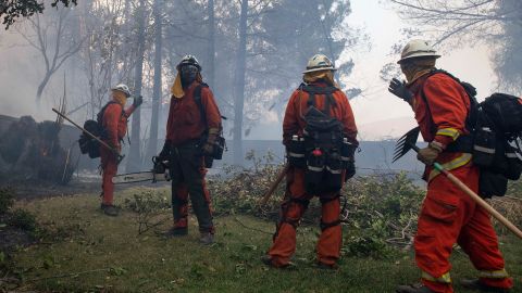 Firefighters from Holton Fire Camp 16 work to contain the Tick Fire behind a home in the Santa Clarita area of Los Angeles on Thursday, October 24, 2019.