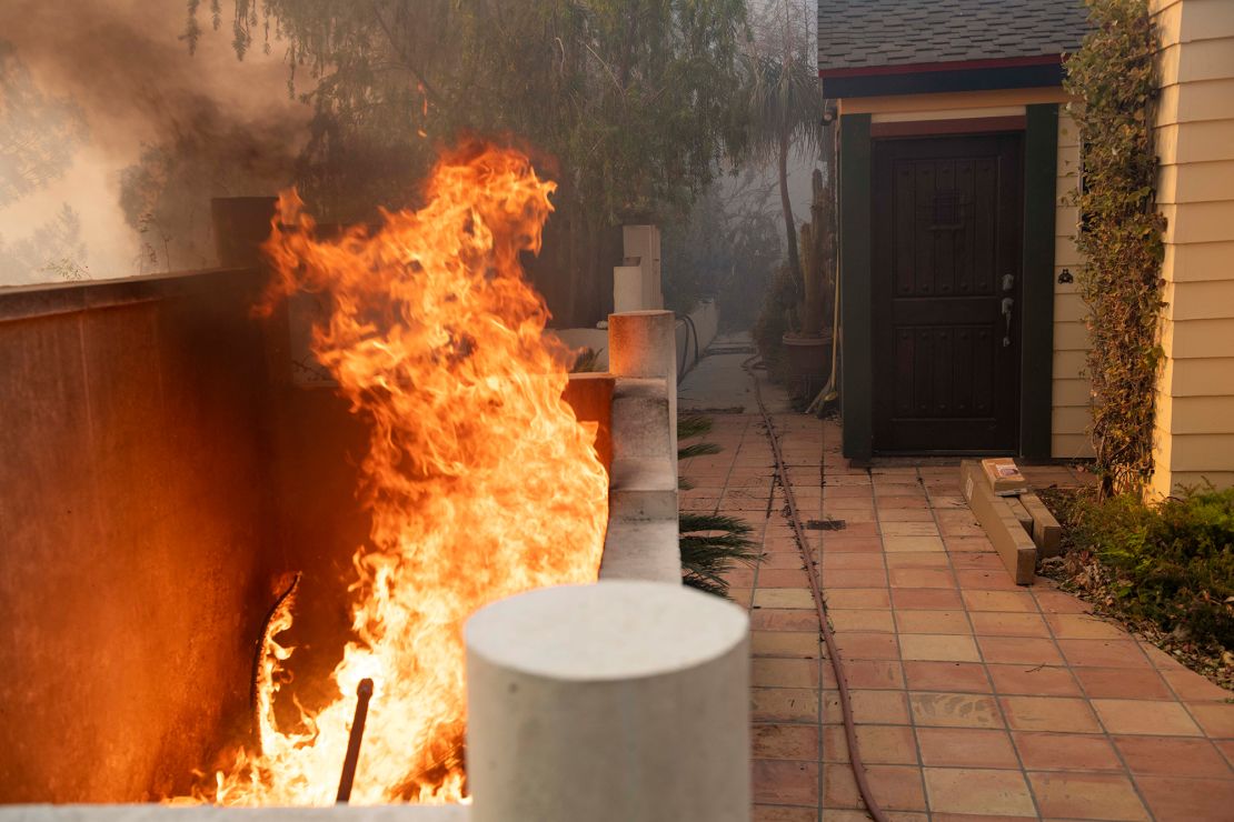 Flames burn near the entrance of a home during the Tick Fire in the Santa Clarita area of Los Angeles on Thursday.