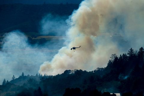 A helicopter passes a smoke plume on Thursday. 