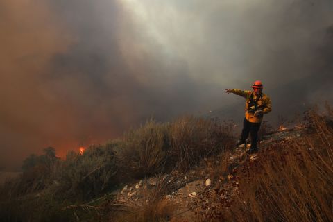A Los Angeles County firefighter monitors the area as the Tick Fire burns near homes in Canyon Country on October 24.