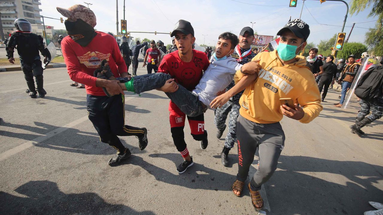 Iraqis carry a wounded demonstrator after security forces fired tear gas to disperse anti-government protests in Baghdad on October 25.
