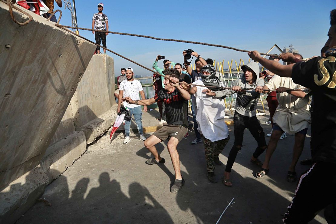 Anti-government protesters pull down concrete walls leading to the heavily guarded Green Zone.