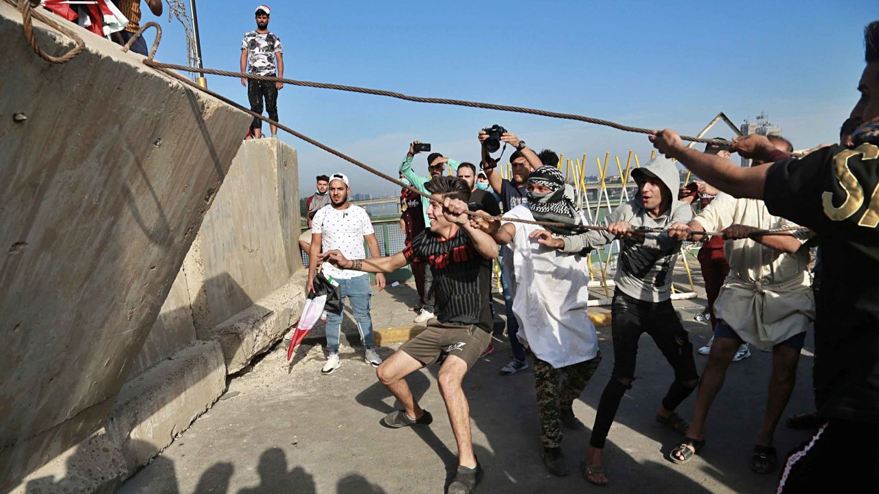 Anti-government protesters pull down concrete walls leading to the heavily guarded Green Zone.