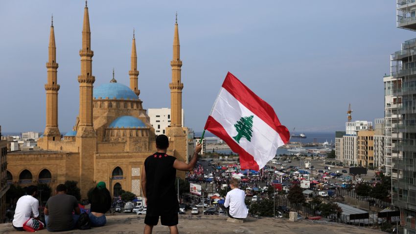 An anti-government protester holds up a Lebanese national flag during a protest in Beirut, Lebanon, Friday, Oct. 25, 2019. Leader of Lebanon's Hezbollah calls on his supporters to leave the protests to avoid friction and seek dialogue instead. (AP Photo/Hassan Ammar)