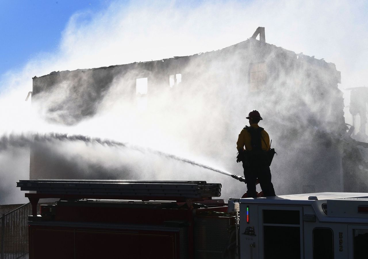 Firefighters hose down a burning house in Agua Dulce, California, on Friday, October 25. It was affected by the Tick Fire, which broke out near Santa Clarita.