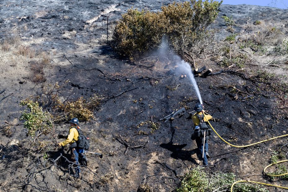 Orange County firefighters put out remaining hot spots from a brush fire in San Clemente, California, on October 25.