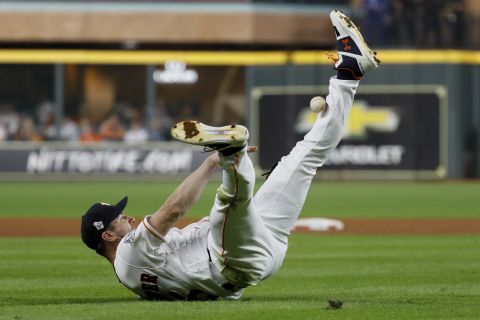 Houston pitcher Justin Verlander dives to the ground and tries to make a throw to first, but he hit his leg instead.
