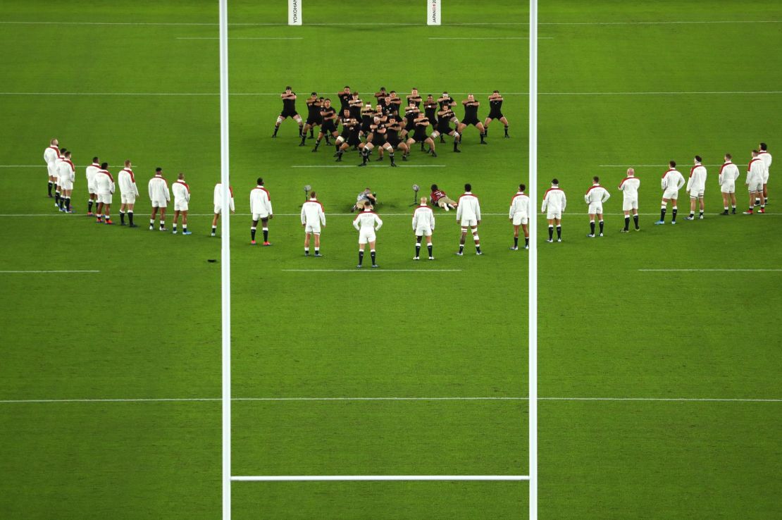 England players stand in an inverted 'V' while New Zealand players perform the haka.