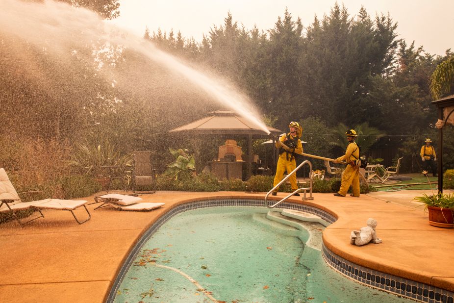 Firefighters battling the Kincade Fire spray water at a home in Windsor on Sunday, October 27.