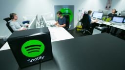 A Spotify Ltd. logo sits on display as employees work at desktop computers inside the music streaming company's offices in Berlin, Germany, on Friday, June 17, 2016. According to reports, Spotify has hired Paul Vogel, the former equity research analyst at Barclays Plc, indicating that the music streaming company may be planning making an initial public offering. Photographer: Krisztian Bocsi/Bloomberg via Getty Images