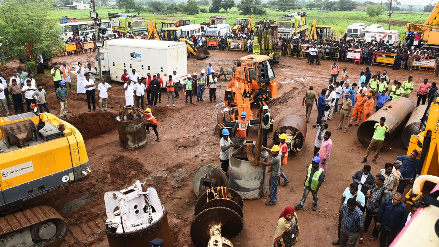 Rescue workers gather with heavy digging equipment during an operation to rescue a toddler stuck in a deep well.