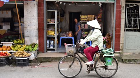 A local woman cycles past a shop in Dong Ngac