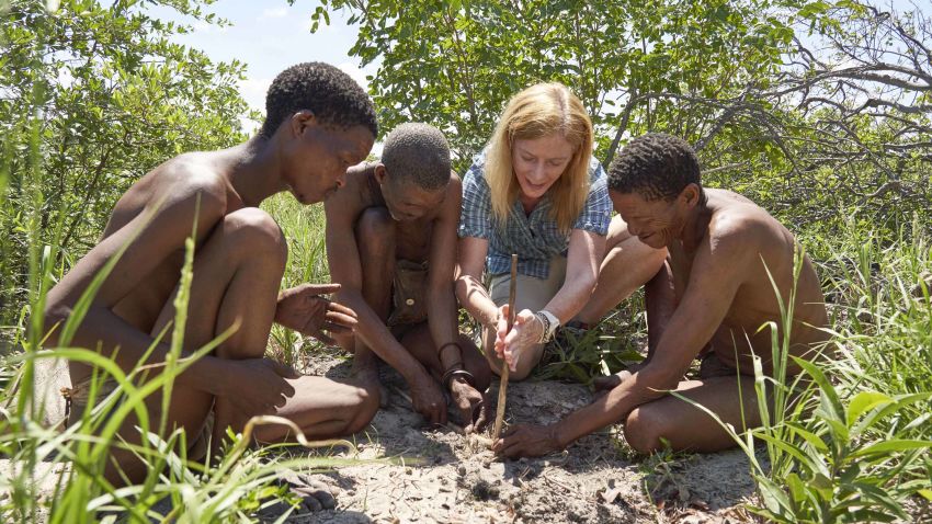 Professor Vanessa Hayes learning how to make fire with Ju?'hoansi hunters in the now dried homeland of the greater Kalahari of Namibia. From left to right: N?amce Sao, ?kun N?amce, Vanessa Hayes and ?kun ?kunta.
