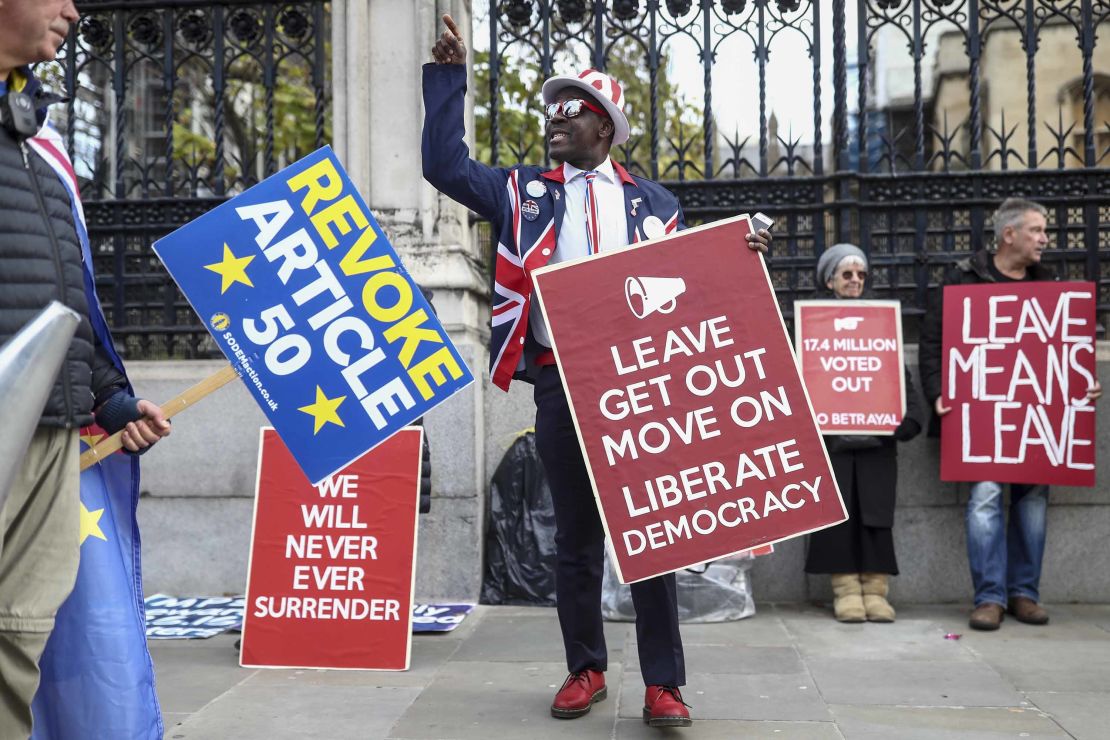 An anti-Brexit demonstrator, left, passes pro-Brexit demonstrators holding placards near the Houses of Parliament in London, in October 2019.