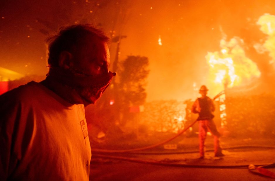A man walks past a burning home in Los Angeles on October 28.
