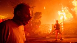 A man walks past a burning home during the Getty fire, Monday, Oct. 28, 2019, in Los Angeles, Calif. (AP Photo/ Christian Monterrosa)