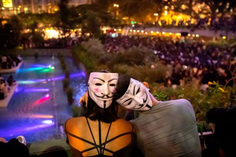 A couple wearing Guy Fawkes masks watch a rally at Chater Garden in Hong Kong on October 26.
