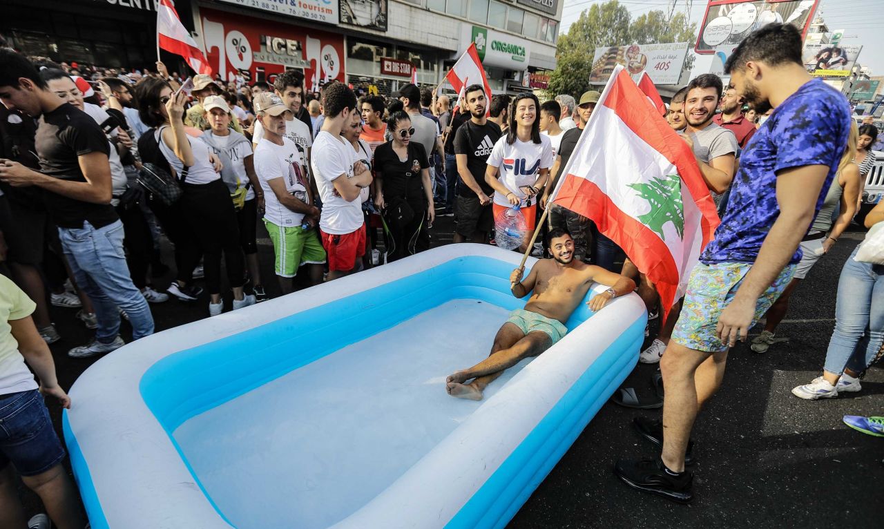 A protester holds a Lebanese flag as he sits in an inflatable pool on a highway in the town of Zouk Mosbeh on October 19.