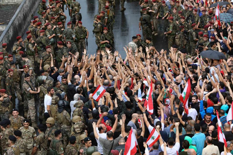 Anti-government protesters wave flags and shout slogans as Lebanese soldiers encircle them on October 23.