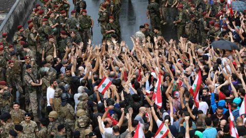 Anti-government protester wave national flags and shout slogans as Lebanese army soldiers face them in the area of Jal al-Dib in the northern outskirts of the Lebanese capital Beirut, on October 23, 2019. - A week of unprecedented Lebanese street protests against the political class showed no signs of abating today, despite the army moving to reopen key roads.Protests sparked on October 17 by a proposed tax on WhatsApp and other messaging apps have morphed into an unprecedented cross-sectarian street mobilisation against the political class. (Photo by Anwar AMRO / AFP) (Photo by ANWAR AMRO/AFP via Getty Images)