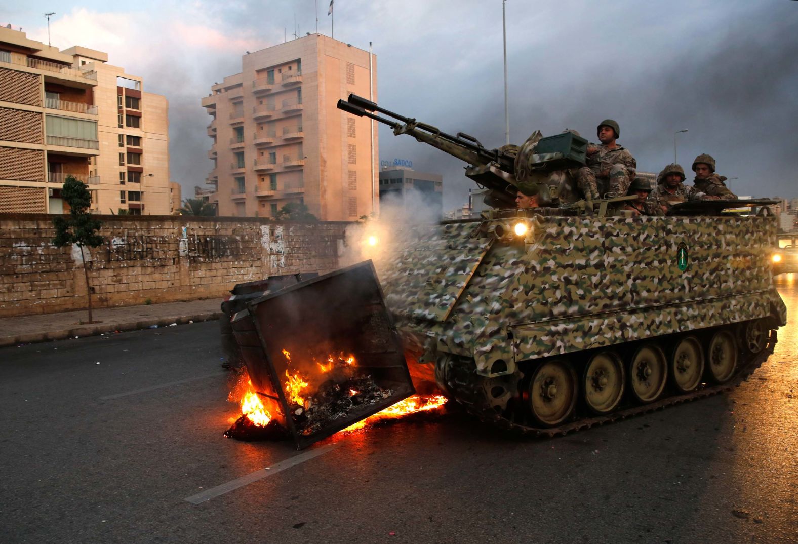 An armored personnel carrier removes a burning garbage container set alight by anti-government protesters on Monday, October 28.