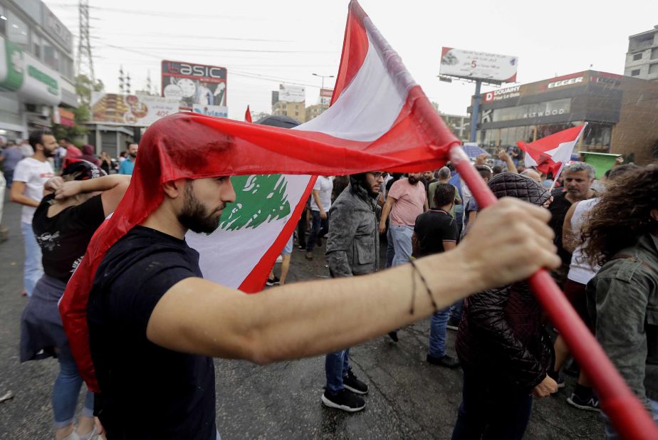 A protester uses a national flag to cover himself as it rains during a demonstration on Wednesday, October 23.