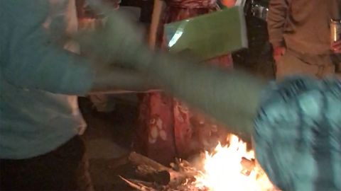 An image taken from video shows a book being thrown into a fire at the party.