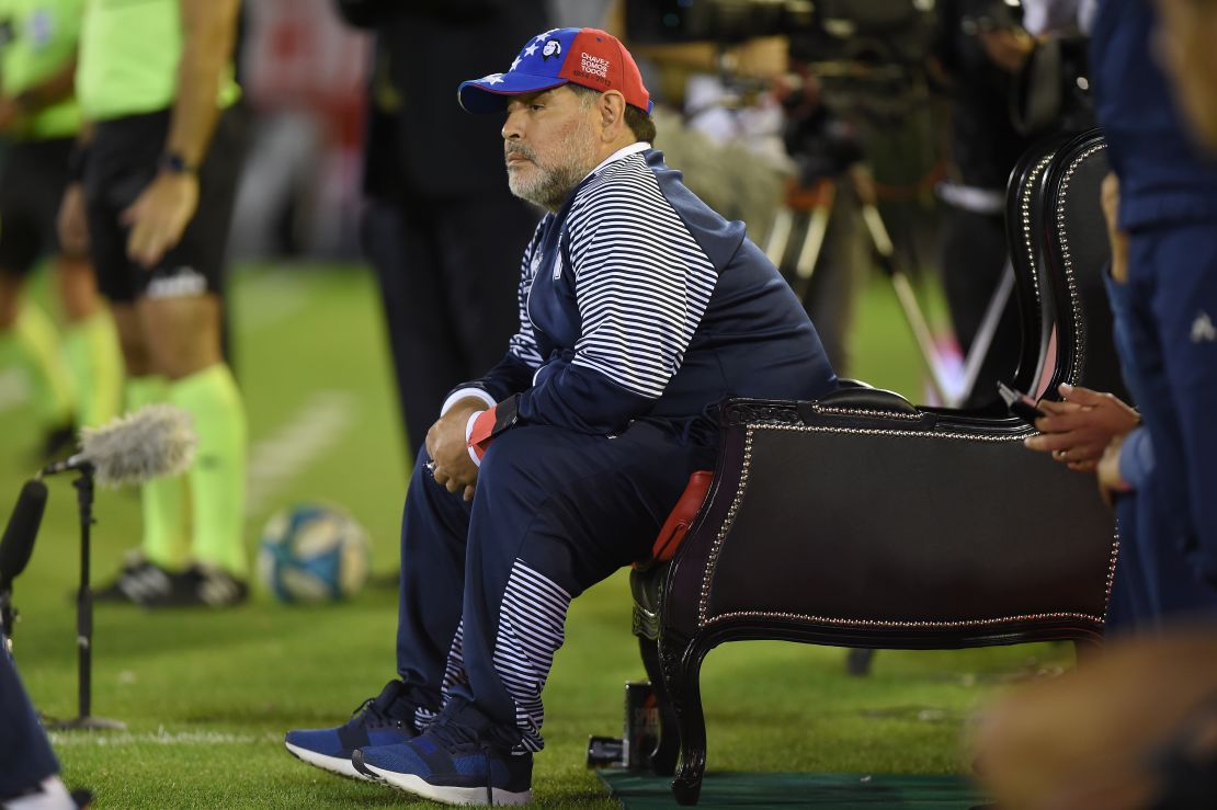 Diego Maradona directs his Gimnasia team from a pitch side throne.