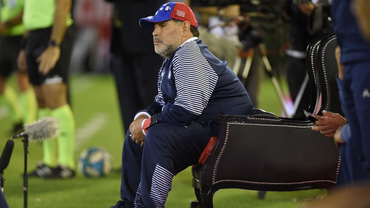 Diego Maradona directs his Gimnasia team from a pitch side throne.