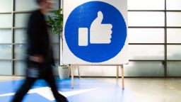 A Facebook employee walks by a sign displaying the "like" sign at Facebook's corporate headquarters campus in Menlo Park, California, on October 23, 2019. (Photo by Josh Edelson / AFP) (Photo by JOSH EDELSON/AFP via Getty Images)