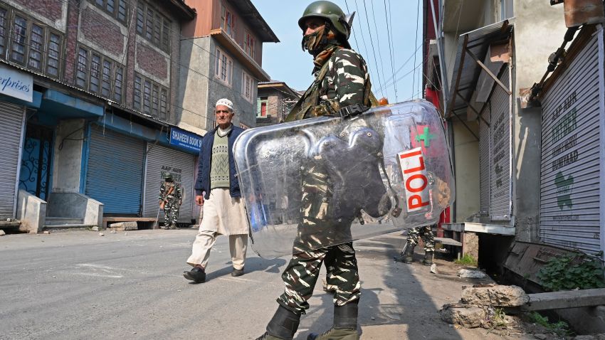 TOPSHOT - A resident walks past Indian paramilitary troopers standing guard during a lockdown in Srinagar on October 29, 2019. - Nearly 30 Euro MPs, drawn mainly from extreme right-wing parties, are on October 29 becoming the first international delegation to visit Indian Kashmir since authorities imposed a security clampdown in August to back the ending of the region's autonomy. (Photo by Tauseef MUSTAFA / AFP) (Photo by TAUSEEF MUSTAFA/AFP via Getty Images)