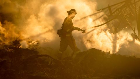 A firefighter sprays down the smoldering remains of a burning home in San Bernardino, California, on Thursday, October 31. It was affected by the Hillside Fire.