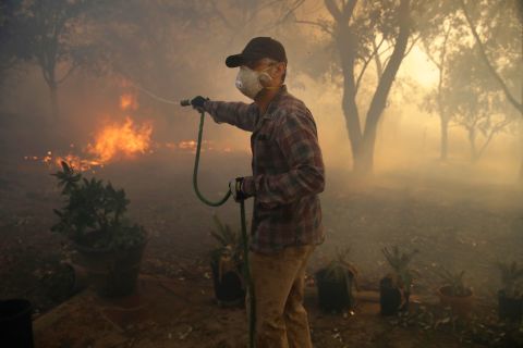 Marco Alcaraz uses a garden hose to try to slow down the advance of the Easy Fire in Simi Valley.