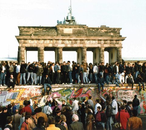 People walk on the Berlin Wall in front of the Brandenburg Gate on November 10, 1989. 
