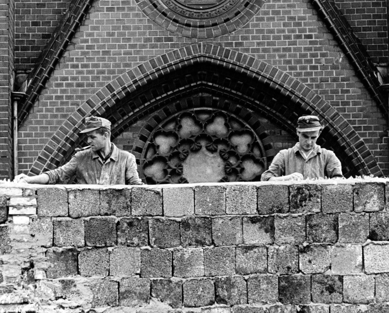 East German workers embed broken glass in the top of the Berlin Wall on August 22, 1961, shortly after construction began.  