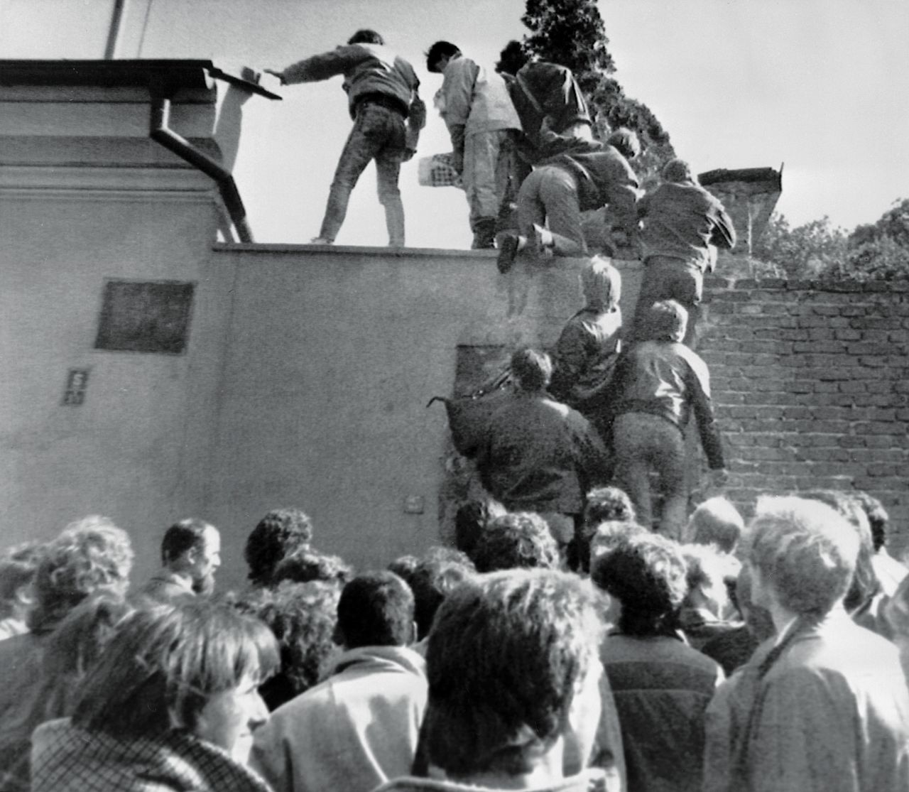 East German citizens scale the walls of the West German embassy in Prague in October 1989, in a desperate first step to freedom.