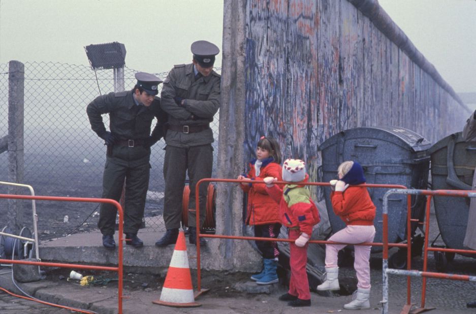 West German children interact with East German border guards after the fall of the Berlin Wall in 1989. 