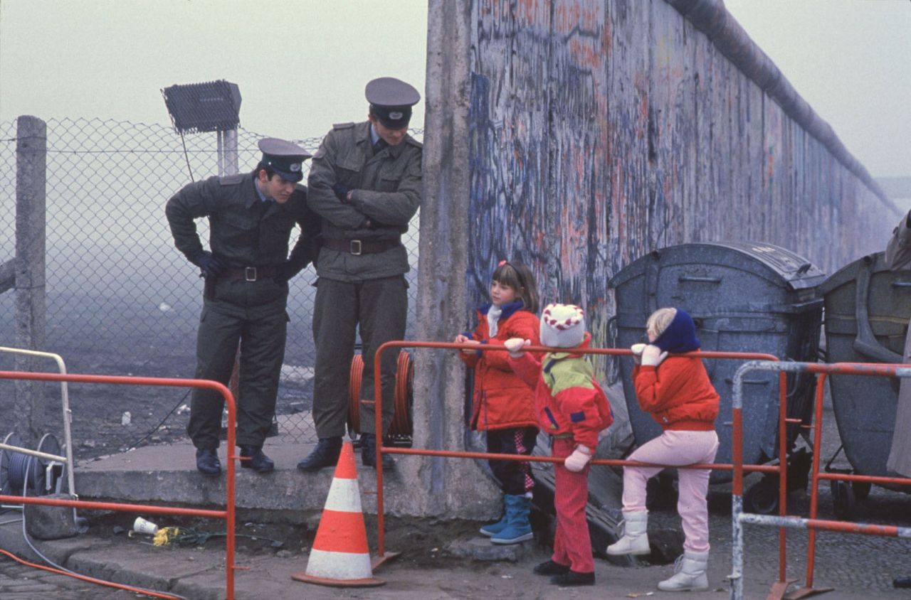 West German children interact with East German border guards after the fall of the Berlin Wall in 1989. 