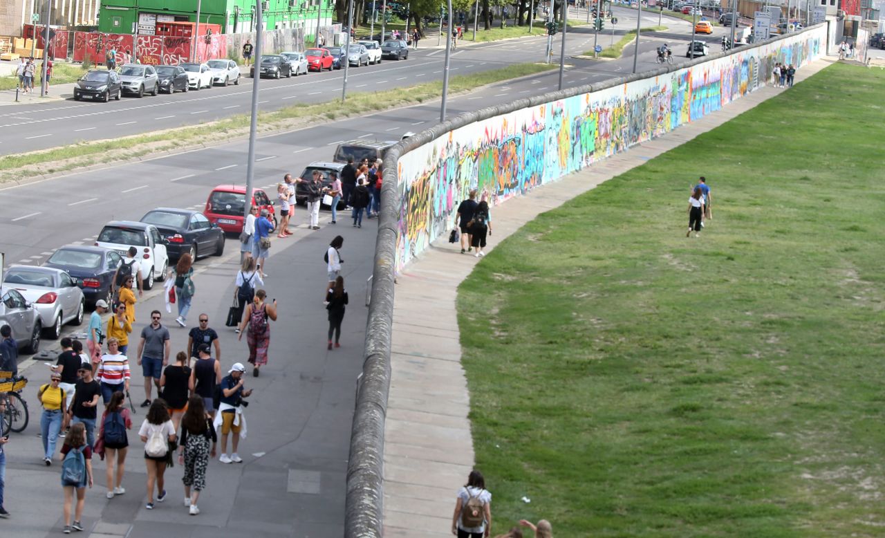People walk along the longest remaining section of the Wall, now known as the East Side Gallery, in August this year. 