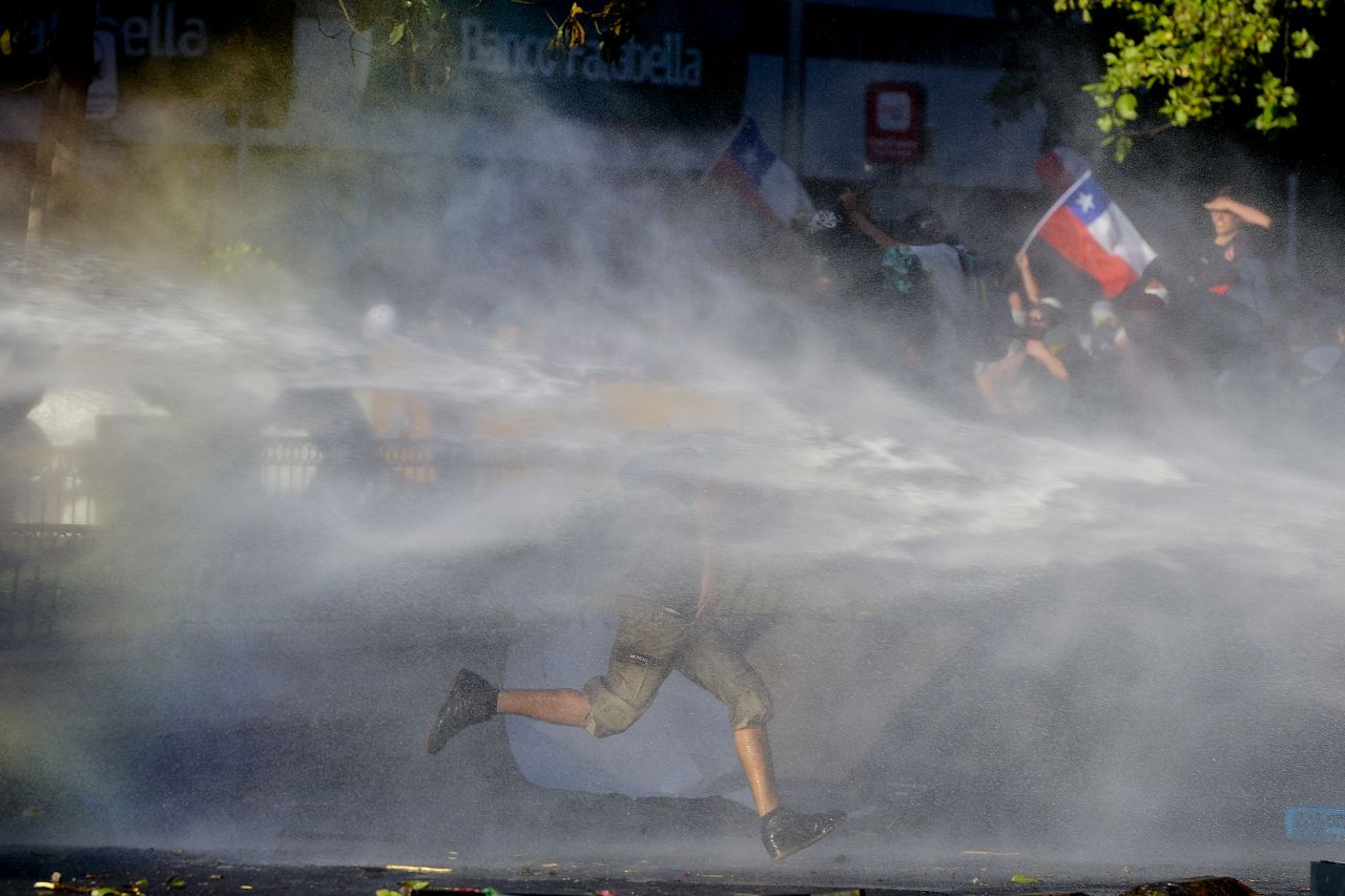 An anti-government protester runs through spray from a police water cannon in Santiago, Chile, on Monday, October 28. <a href="https://www.cnn.com/2019/10/28/americas/chile-pinera-cabinet-protests-intl-hnk/index.html" target="_blank">Violent protests</a> have paralyzed the country, seen the military return to the streets and led to the deaths of at least 20 people. Chilean President Sebastian Pinera has promised social and economic reforms to tackle issues at the heart of the unrest.