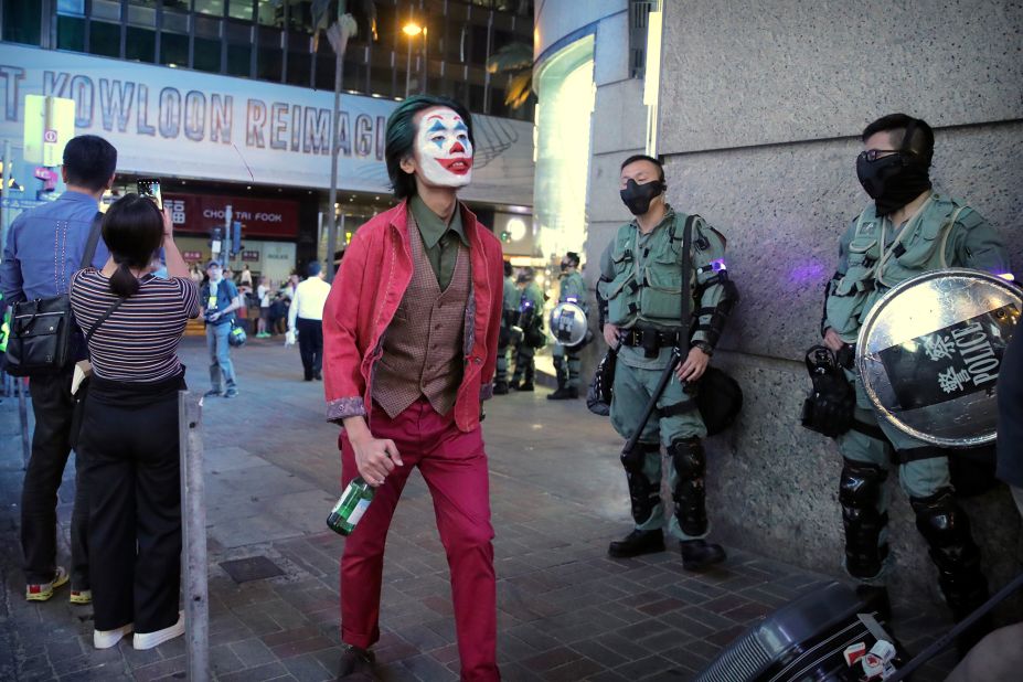 A man dressed as the Joker for Halloween walks past police officers on October 31. 