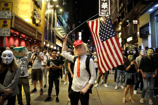 A person dressed as President Donald Trump waves an American flag on a street in Hong Kong on Thursday, October 31, 2019. Hong Kong authorities braced as pro-democracy protesters urged people on Thursday to celebrate Halloween by wearing masks on a march in defiance of a <a href="index.php?page=&url=https%3A%2F%2Fwww.cnn.com%2F2019%2F10%2F30%2Fasia%2Fhalloween-hong-kong-mask-ban-intl-hnk%2Findex.html" target="_blank">government ban on face coverings</a>. 
