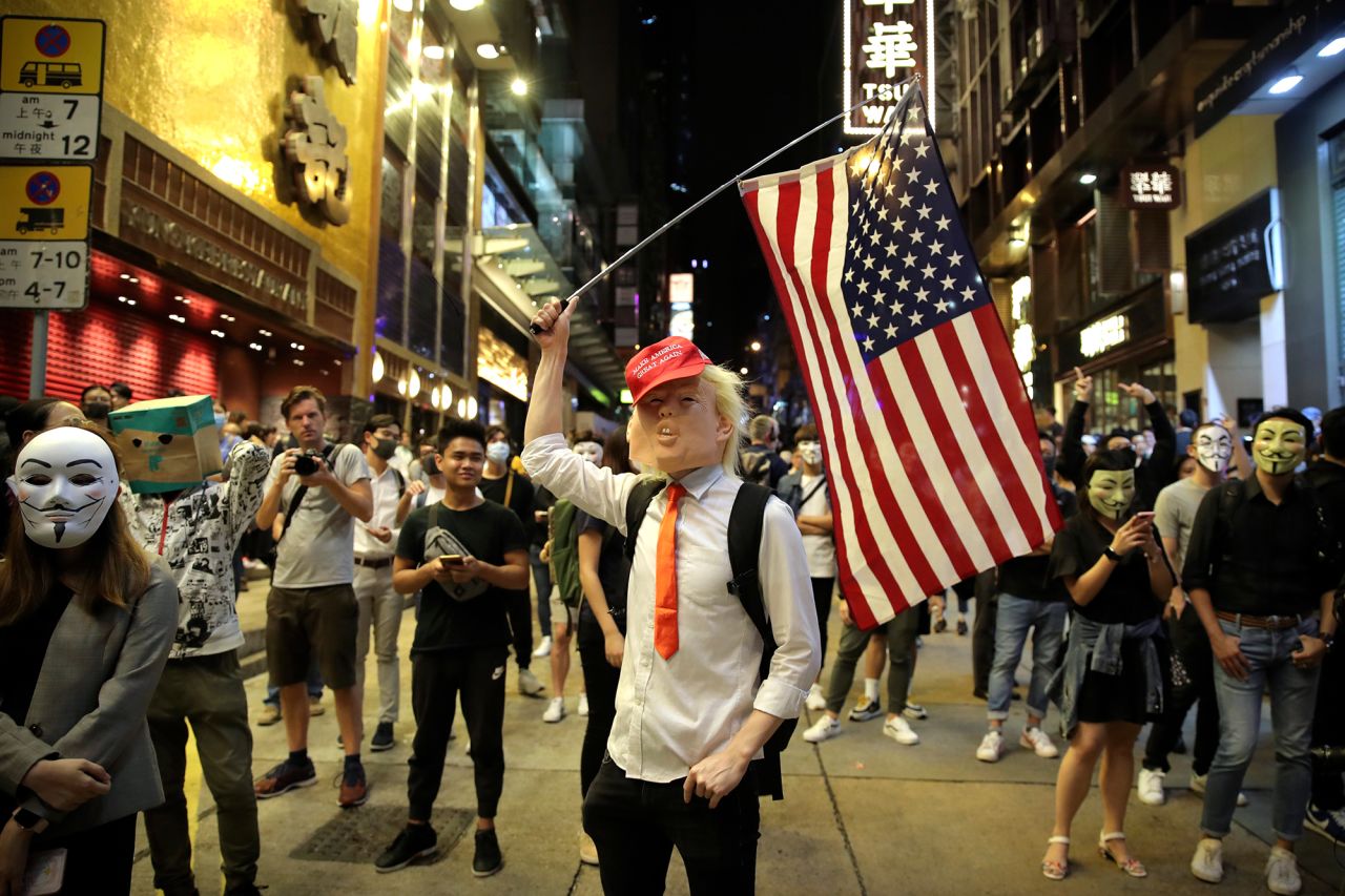 A person dressed as President Donald Trump waves an American flag on a street in Hong Kong on Thursday, October 31, 2019. Hong Kong authorities braced as pro-democracy protesters urged people on Thursday to celebrate Halloween by wearing masks on a march in defiance of a <a href="https://www.cnn.com/2019/10/30/asia/halloween-hong-kong-mask-ban-intl-hnk/index.html" target="_blank">government ban on face coverings</a>. 