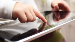 Close-up of a child playing on a touch screen tablet.
