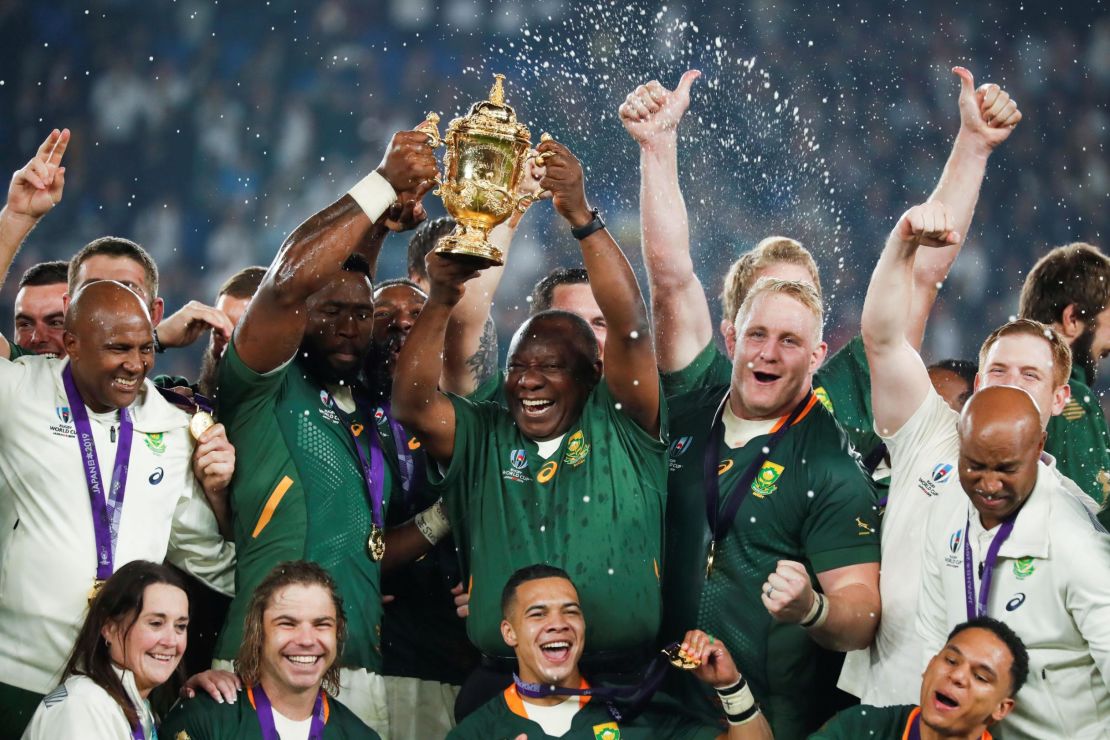 South Africa's President Cyril Ramaphosa (centre R) and Kolisi (centre L) lift the trophy.