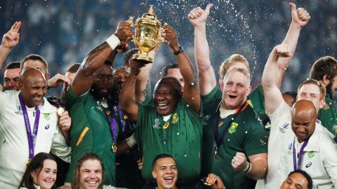 South Africa's President Cyril Ramaphosa (centre R) and Kolisi (centre L) lift the trophy.
