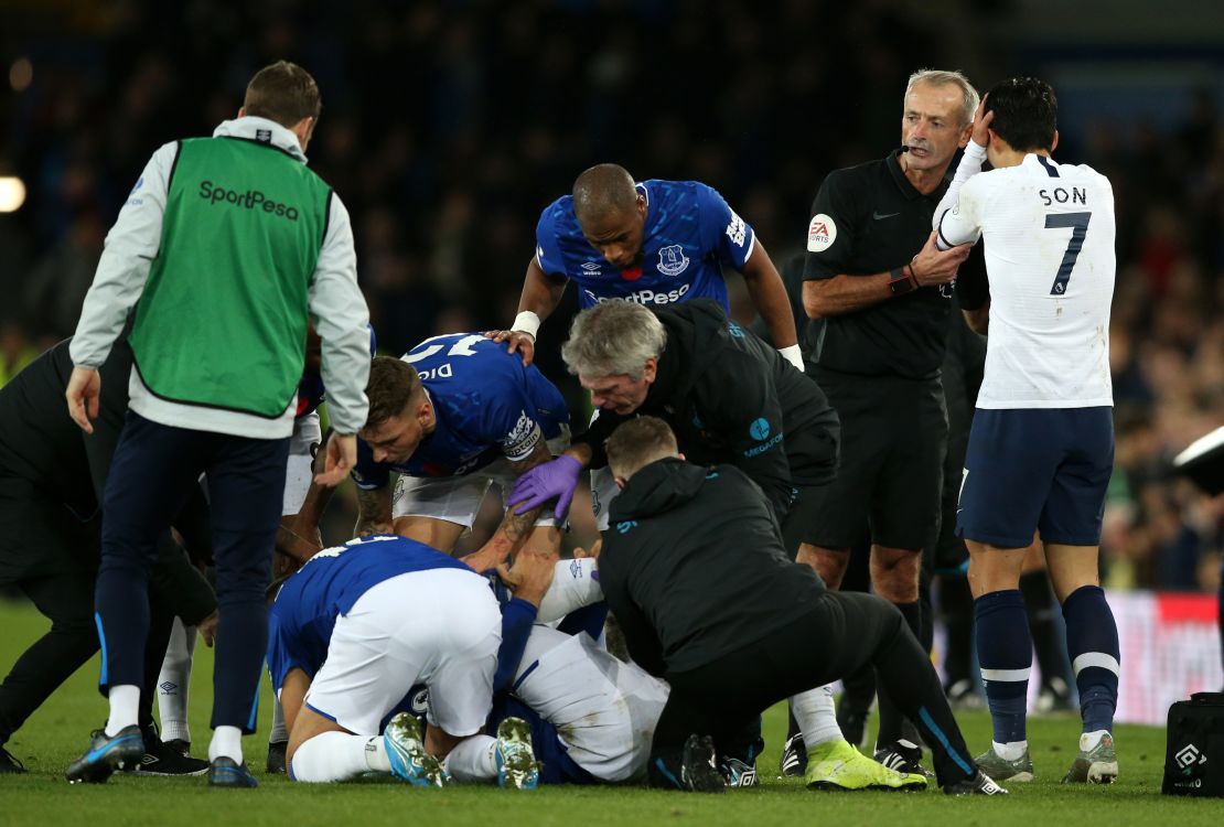 Match referee Martin Atkinson consoles Son Heung-Min as Everton players and medical staff cluster around the stricken Andre Gomes. 